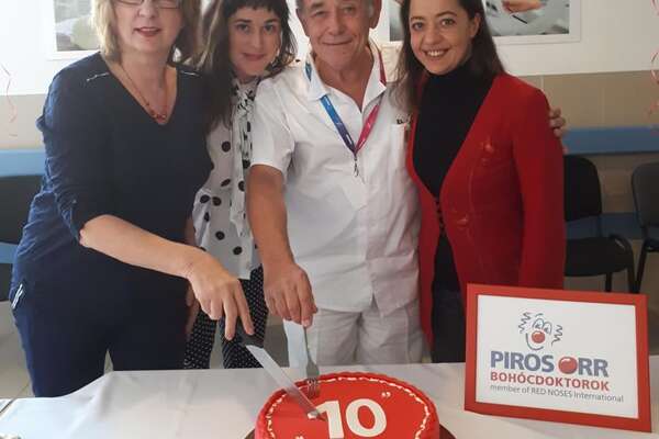 Egy orvos és három nő egy ünnepi tortát vág fel