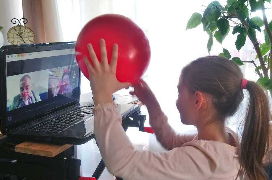 Online vizit Kislány videótelefonáló bohócdoktorokat néz egy laptopon